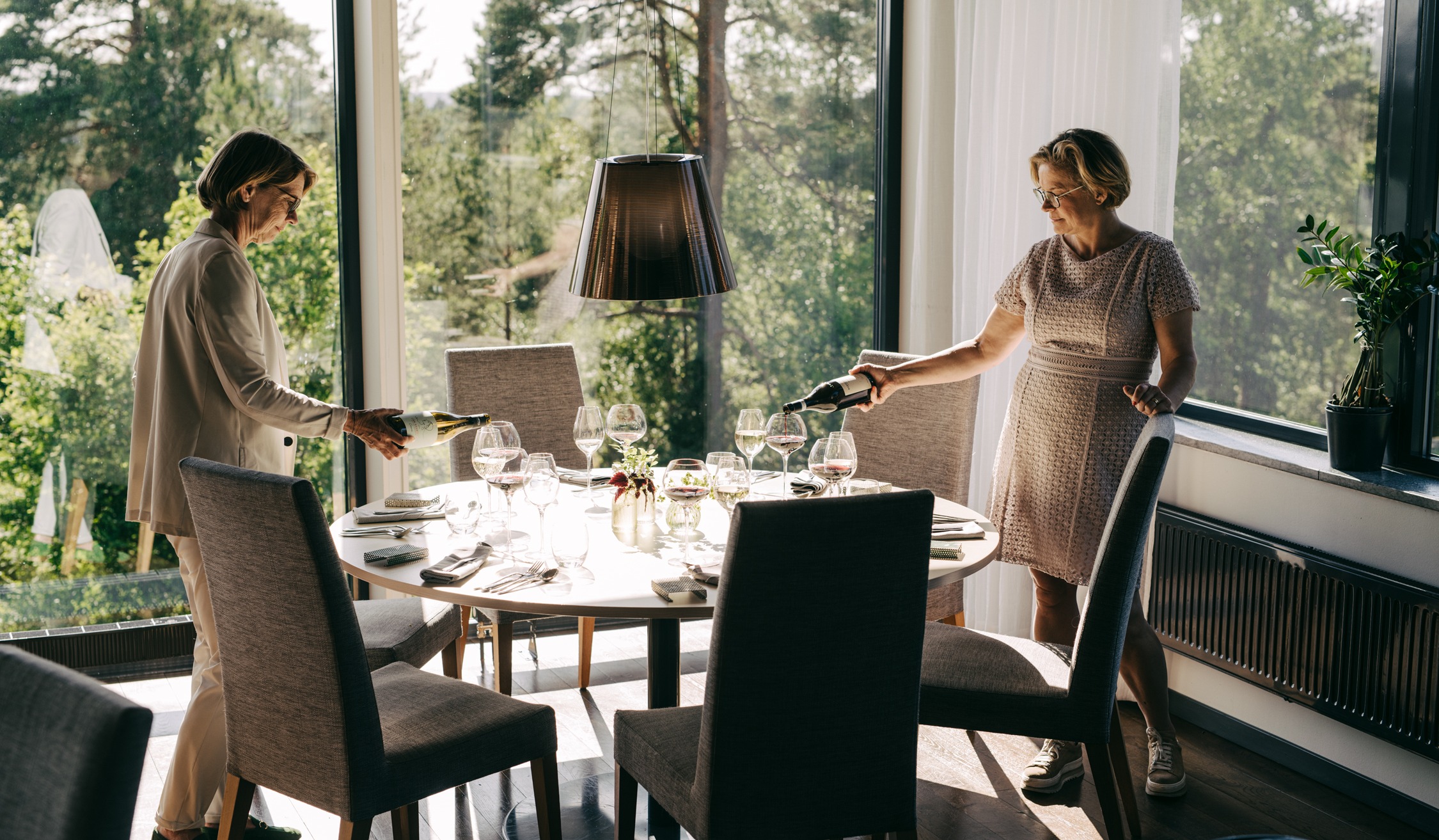 Lotta Boman och Lena Andersson från Sigtunahöjden som häller upp vin i Restaurang Skogs matsal